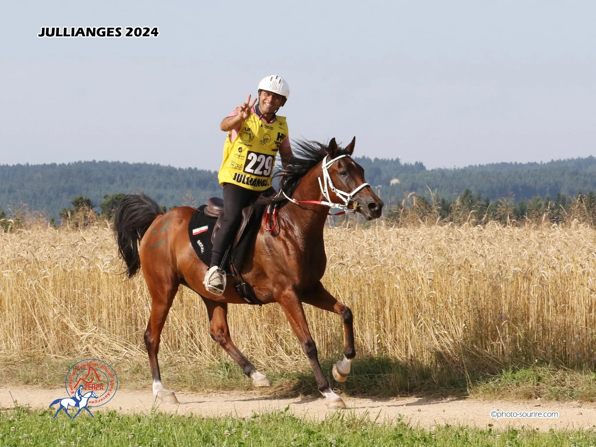 Cavalier souriant en chemise jaune sur un cheval bai, sur un chemin de campagne
